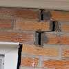 A brick wall displaying stair-step cracks and messy tuckpointing on a Salinas home